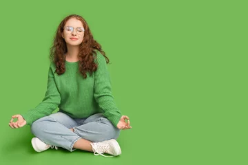  Portrait of relaxed young woman meditating on green background © Pixel-Shot