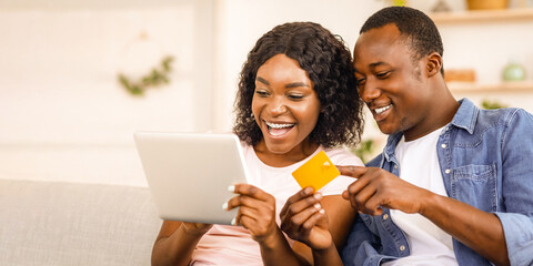 Closeup of black couple making purchases online, holding digital tablet and credit card, free space