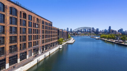 Obraz premium Sydney waterfront view featuring historic brick building and bridge