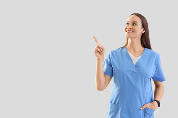 Female medical intern pointing at something on light background
