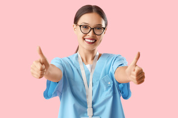Asian medical intern showing thumbs-up on pink background