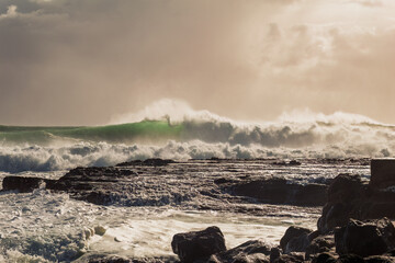 A moody, atmospheric photo of heavy surf and crashing breakers driven by an approaching cyclone or...