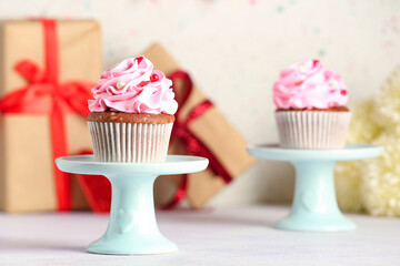Stand with tasty cupcake for Valentine's Day on light background