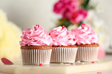 Board with tasty cupcakes for Valentine's Day on tile table