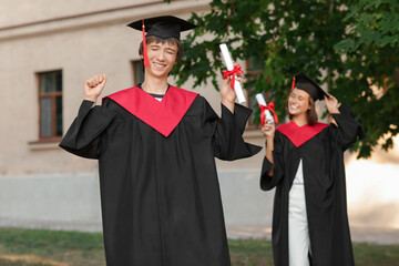 Graduating students with diplomas outdoors