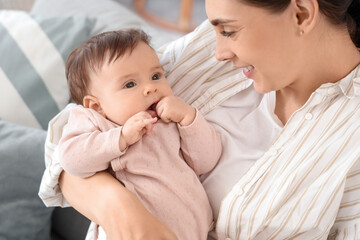 Mother with her little baby sitting on sofa at home, closeup