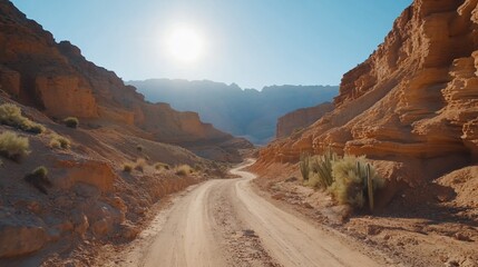 Winding dirt road through majestic canyon under bright sun