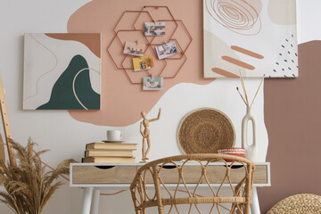 Stylish artist's workspace with books and mood board hanging on wall