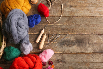 Composition with different wool for felting and needles on wooden background