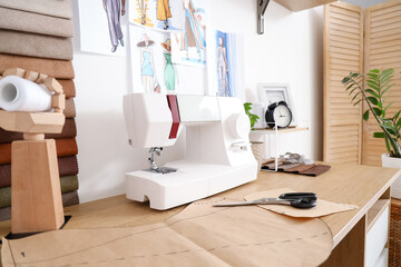 Sewing machine with patterns on tailor's table in atelier