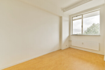 A minimalist empty room featuring a large window that offers a view of greenery outside, highlighting the simplicity and spaciousness of the space.