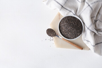 Bowl and spoon with chia seeds on white background