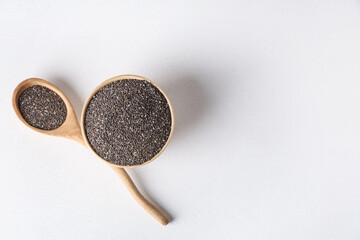 Bowl and wooden spoon with chia seeds on white background