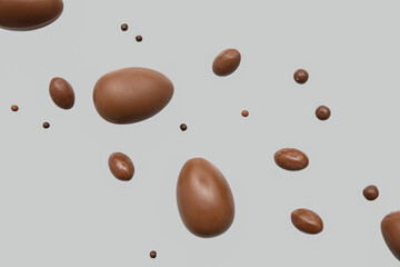 Tasty chocolate eggs flying on grey background