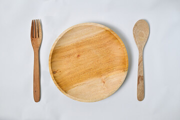 Close up view of empty round wooden plate with wooden spoon and wooden fork isolated on white background with clipping path.