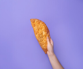 Hands tearing apart a crispy, golden Cheburek with a stretchy filling, set against a bright background. A traditional fried pastry from Eastern European and Central Asian cuisine.