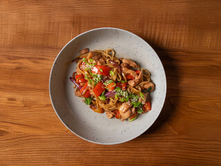 Wok of noodles, vegetables and chicken in soy sauce Chinese food on a yellow background Photo of Chinese food for advertising