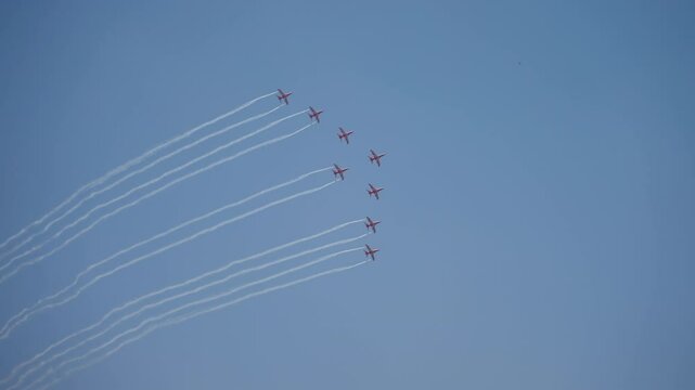 A formation of red jets creating smoke trails at the Aero India Air Show by Surya Kiran Aerobatic Team