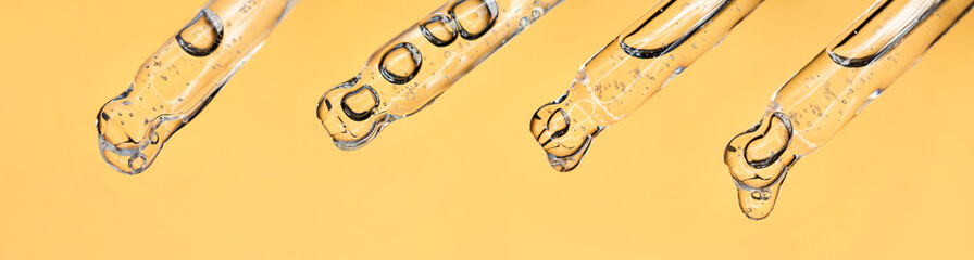 A set of glass pipettes with facial serum on a light background. Essential oil close-up in...