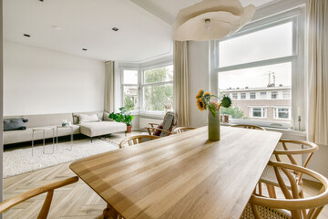 A bright and airy dining space with minimalist decor, featuring a wooden table, stylish chairs, and natural light enhancing the green plants by the window.