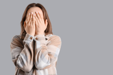Young woman having panic attack on grey background