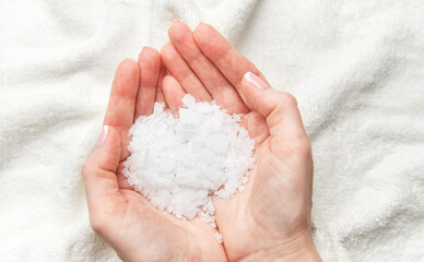 Woman holding white magnesium chloride flakes in hands for a relaxing bath