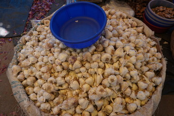 A bag full of garlic and a plastic pot is on the pile