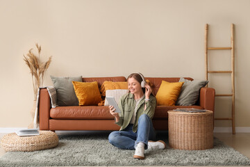 Young woman sitting on floor with tablet computer and headphones in living room