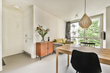 A stylish modern living area featuring a blend of minimalistic design, natural light, and vibrant floral decor. Perfect blend of comfort and aesthetics.