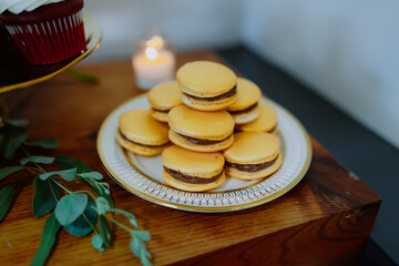 Elegant dessert table with macarons, cupcakes, and candle decor