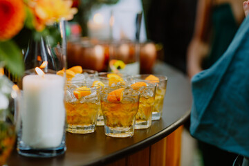 Glasses of whiskey with ice and orange garnish on a bar table