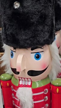 Nutcracker toys are arranged on a store shelf alongside Christmas tree ornaments and festive decorations. a lineup of Nutcracker Soldiers in uniform 