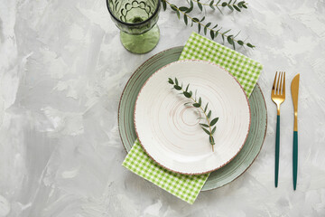 Beautiful table setting with golden cutlery and eucalyptus branches on grey background