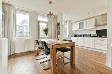 A bright and airy modern dining area featuring a wooden table, stylish chairs, and large windows bringing in ample natural light, creating an inviting atmosphere.