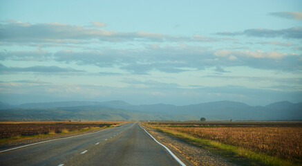 The road in the evening is closer to sunset. Mountains in the distance