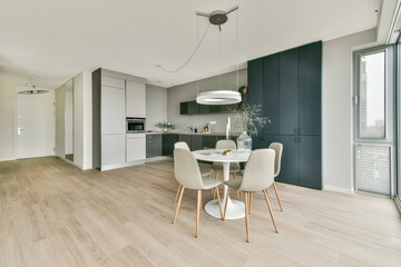 A contemporary kitchen featuring clean lines, a round dining table, stylish chairs, and a mix of light and dark cabinetry, emphasizing functionality and aesthetics.