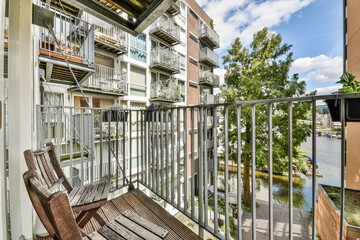 A stylish balcony overlooks a vibrant urban scenery with lush greenery nearby. The architecture blends contemporary design with nature elements.