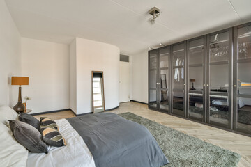 A sleek and contemporary bedroom featuring neutral colors, elegant decor, and ample natural light, perfect for relaxation and comfort.