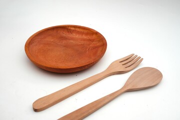 Eco-friendly wooden plate with a fork and spoon on a pristine white background, highlighting sustainable dining.