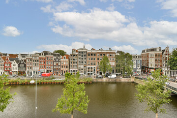 A beautiful view of a riverfront lined with historic buildings and lush greenery under a blue sky, showcasing architectural diversity and natural beauty.