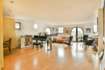 A spacious and bright modern interior featuring a piano, stylish seating, and large windows allowing natural light to illuminate the room. Ideal for relaxation.