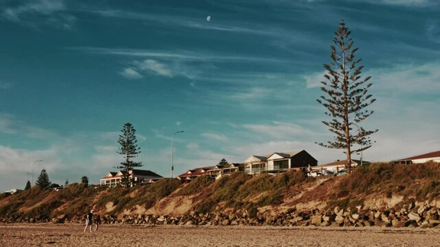 People Walking Seaside Property at Sunset Blue Moody Skies Moon 4K 24fps