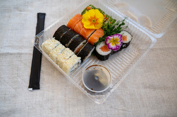 Food delivery concept. Transparent plastic lunch box with sushi set.