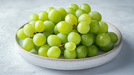 Close up view of a cluster of green grapes on a speckled white plate. The grapes appear fresh and juicy, with visible water droplets.