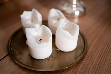 Melted white candles on brass tray with wooden surface background