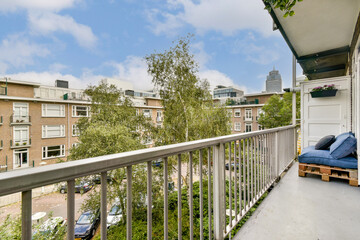 A stylish modern balcony featuring wooden seating and a lush green view, perfect for enjoying the urban skyline and surrounding greenery.