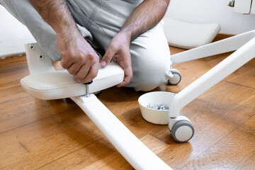 Caucasian male assembling white office chair on wooden floor