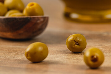 Enjoying fresh green olives on a wooden table with olive oil
