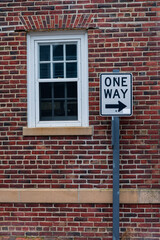 Obraz premium One Way Sign in Front Of A Red Brick Wall