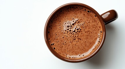 Overhead close up of a brown mug filled with frothy dark brown coffee, on a white background.